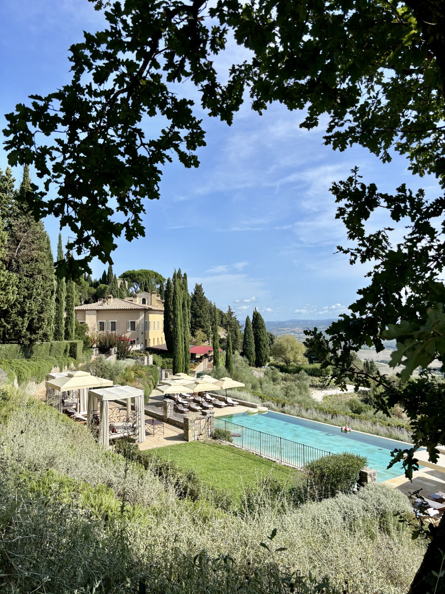 Tuscan villa and swimming pool framed by trees above the countryside